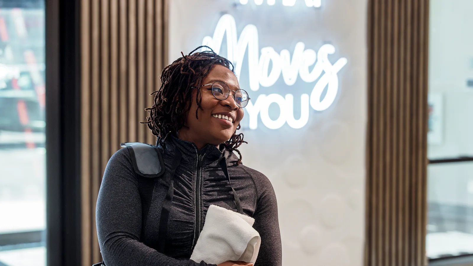Smiling woman in activewear holding a towel, embodying the benefits of a 30 minute workout.