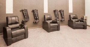 Three reclining chairs with Normatec compression boots in a modern recovery room.