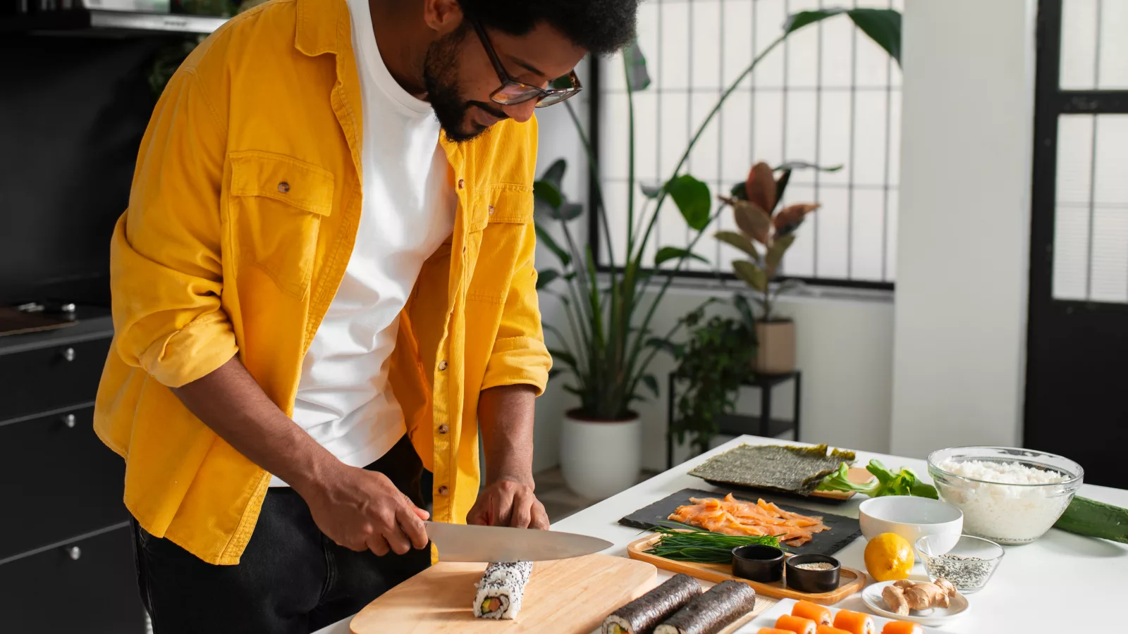 Man preparing sushi in a bright kitchen, showcasing elements of a balanced plate with fresh ingredients.