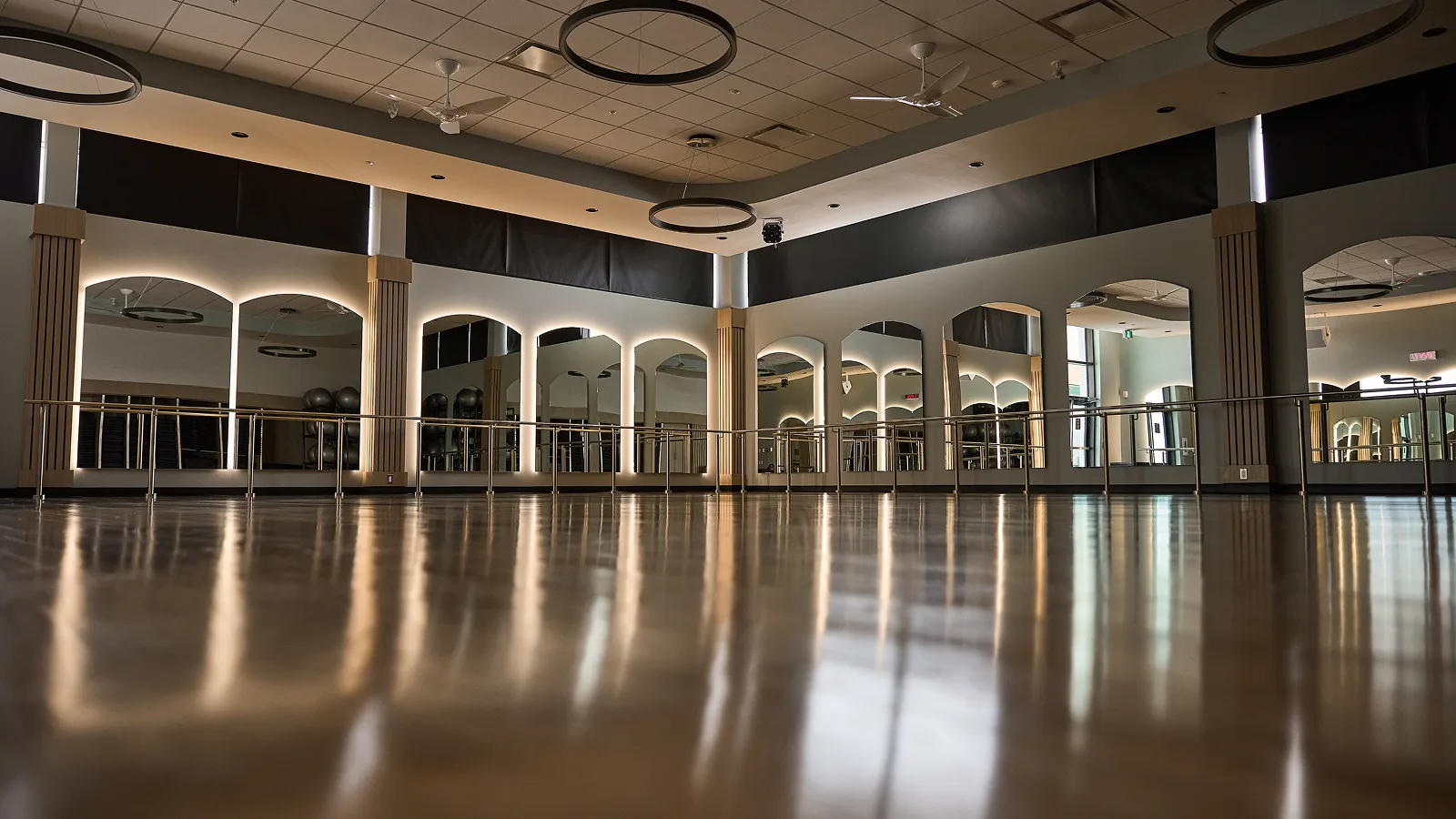Empty barre studio with mirrors and ballet bars, ready for barre classes.