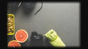 Best post workout meal with grapefruit, protein shake, shoes, and towel on a gym mat.