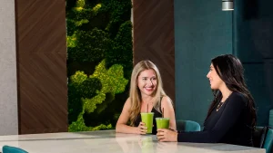 Two women enjoying green smoothies, highlighting the importance of essential nutrients in a modern, stylish setting.