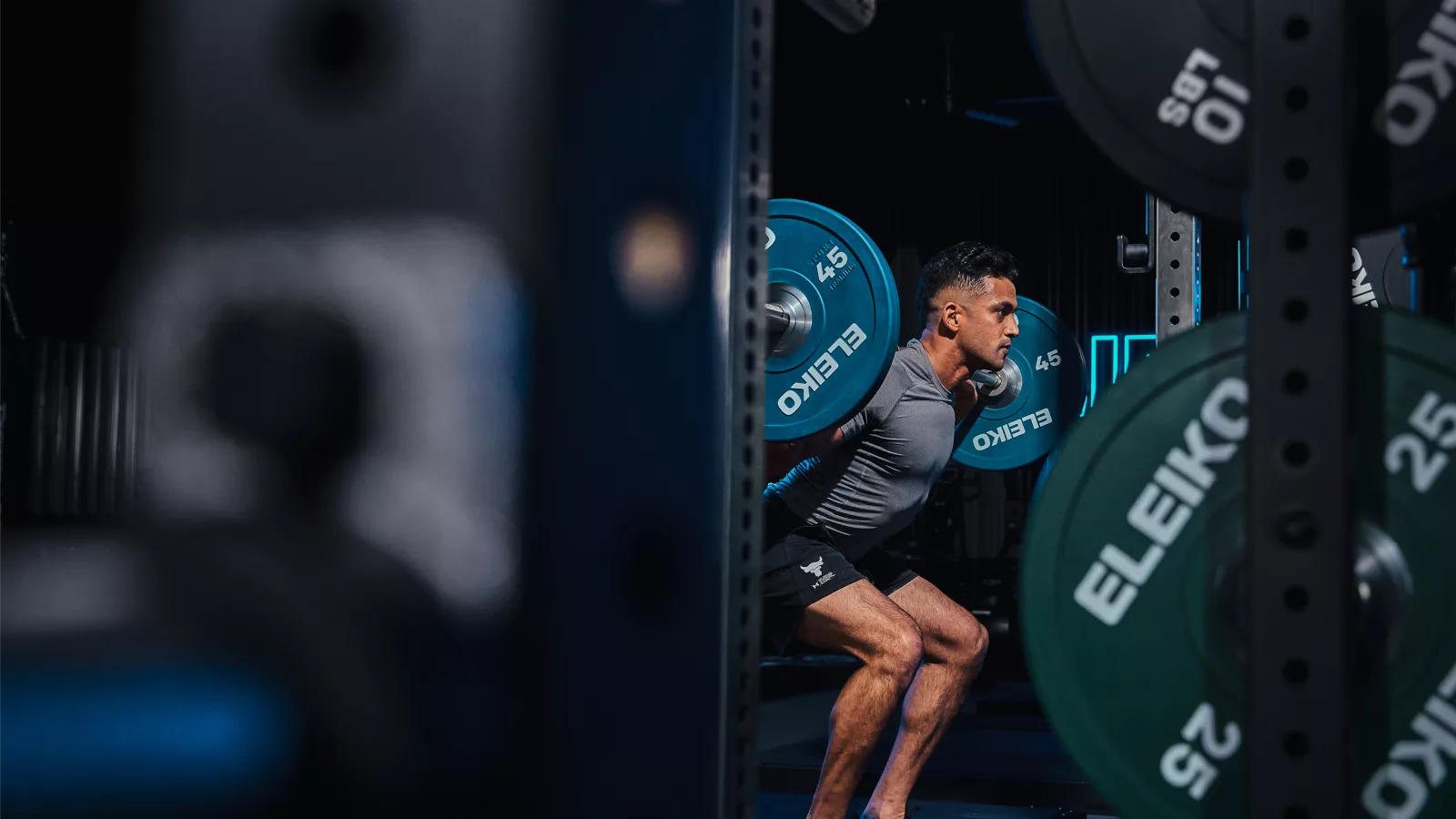 Man performing barbell squats in a gym, highlighting exercise trends 2026 with Eleiko weights.
