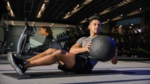 Man performing Russian twists with a medicine ball, showcasing good ab workouts in a gym setting.