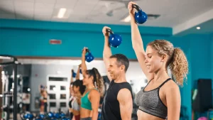 People lifting kettlebells in a group fitness class at a gym.