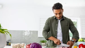 Man chopping vegetables in a kitchen, highlighting gut healthy foods for better digestion and wellness.