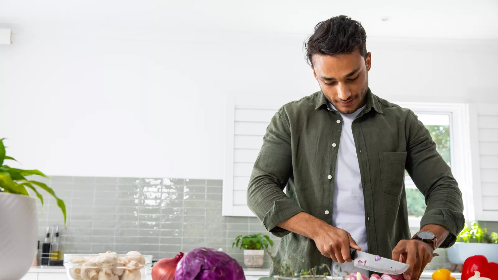 Man chopping vegetables in a kitchen, highlighting gut healthy foods for better digestion and wellness.
