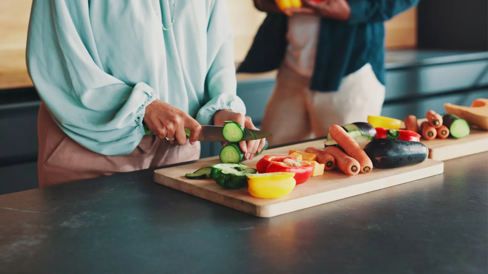People preparing fresh vegetables on a cutting board, highlighting healthy meal planning for busy lifestyles.