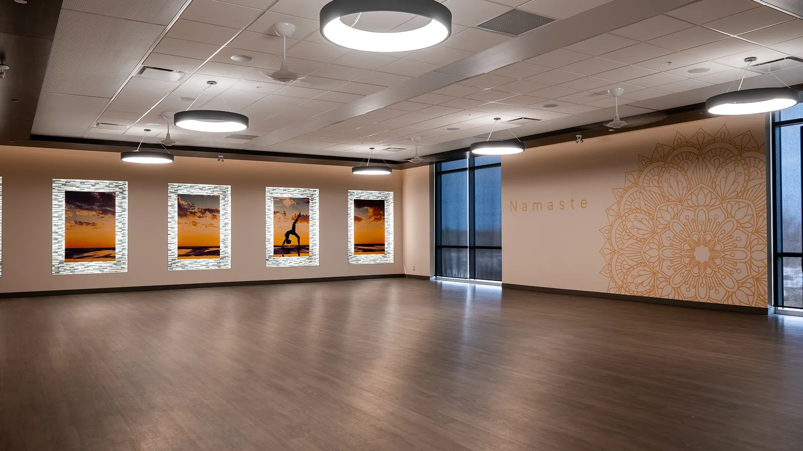 Spacious hot pilates studio with decorative wall art and wooden flooring, ideal for fitness and relaxation.