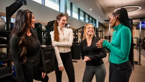 Group of women in activewear at a gym, discussing how to start running together.