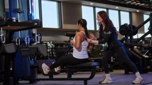 A personal trainer guides a client on gym equipment, highlighting the role of a personal trainer in fitness training.