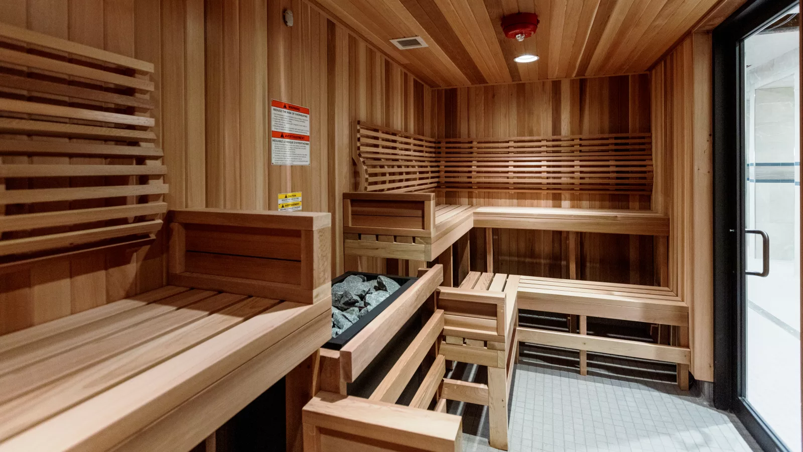 Wooden sauna interior with benches and a heater, highlighting sauna and steam benefits for post-exercise recovery.