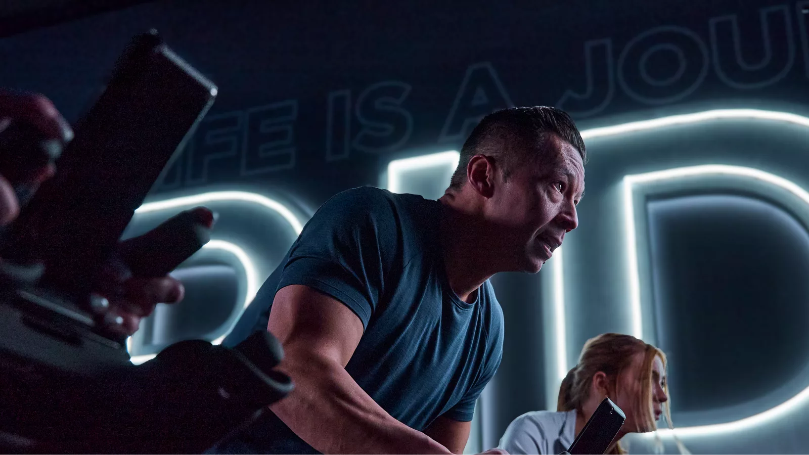 Man intensely cycling in a dimly lit spin class, highlighting spin class popularity.