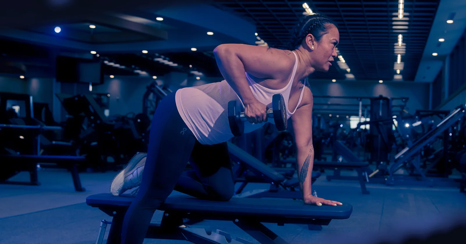 Woman performing dumbbell row in gym, showcasing strength training benefits.